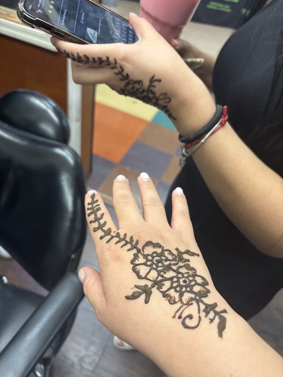 Client holding up a hand with a fresh floral and vine henna tattoo
