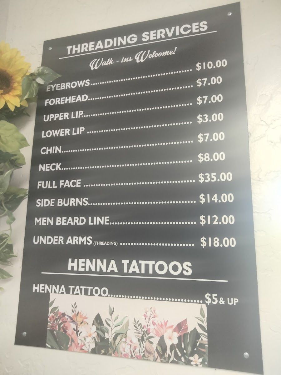 The studio's threading services price board on the wall, with sunflowers beside it