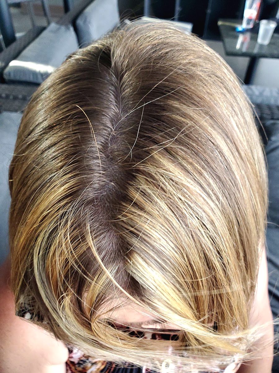 Top-down view of a center part with fine blonde highlights through brunette hair