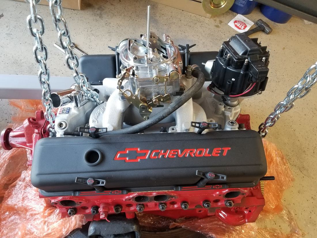 Chevrolet small block engine hanging from a chain hoist