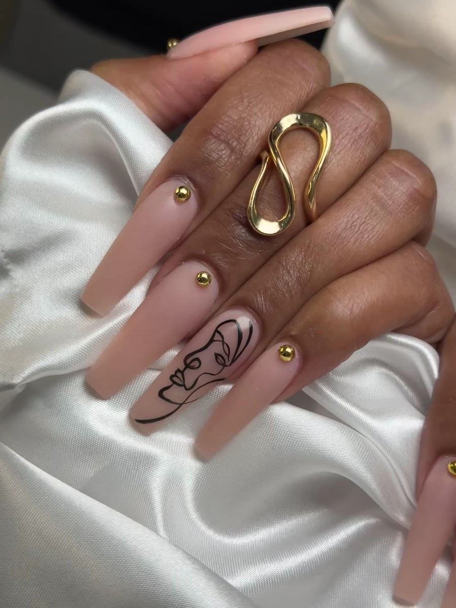 Long nude matte coffin nails with gold studs and line art, done at Galaxy Nails