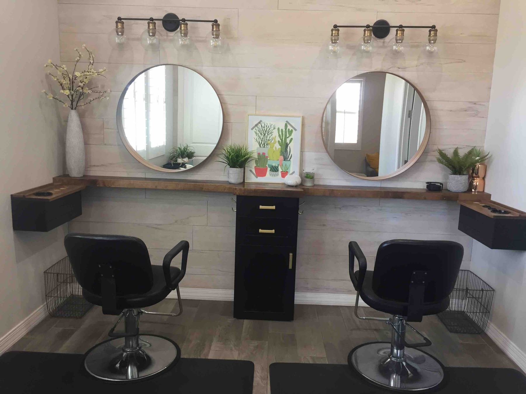 Heather's white studio with two round mirrors, black styling chairs and plants