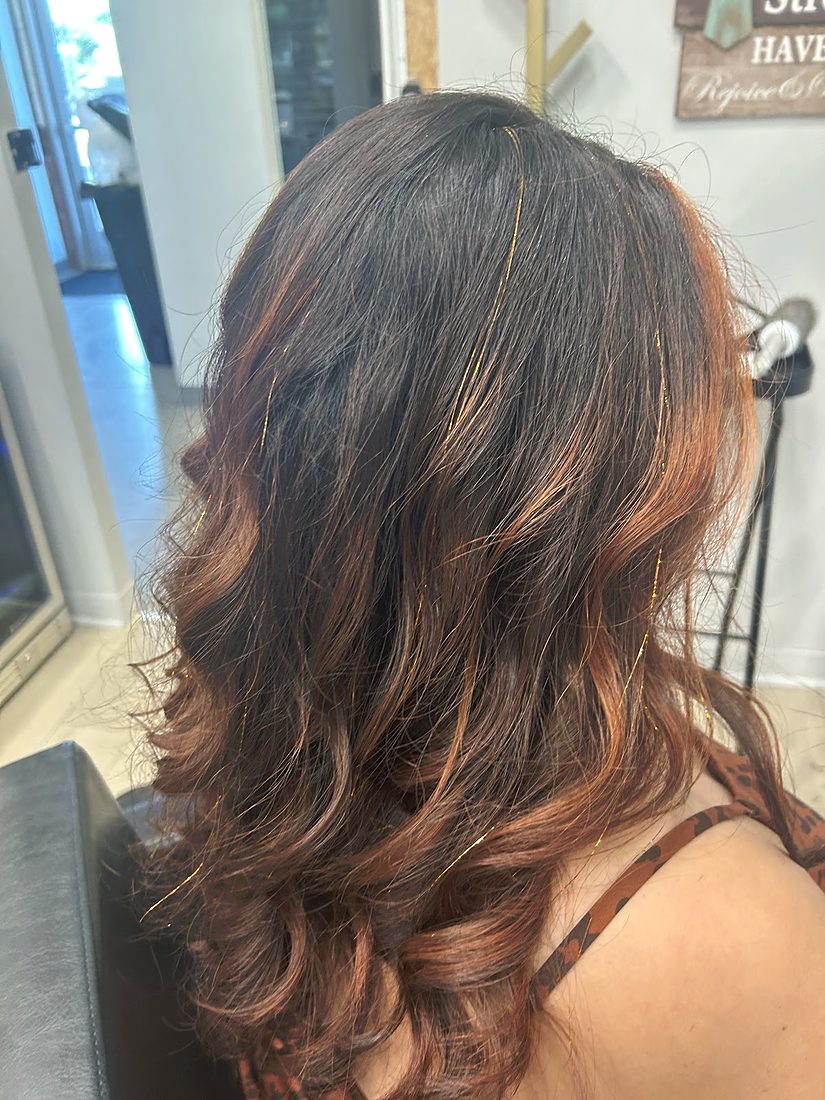 Dark brown hair fading to copper ends, curled, seen from the side