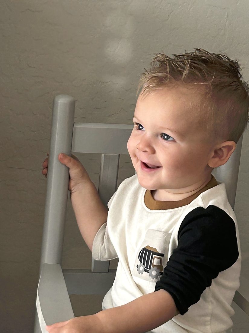 A smiling toddler with a short textured haircut
