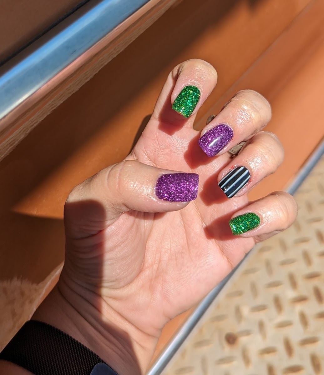 Short nails in green and purple glitter with a striped accent