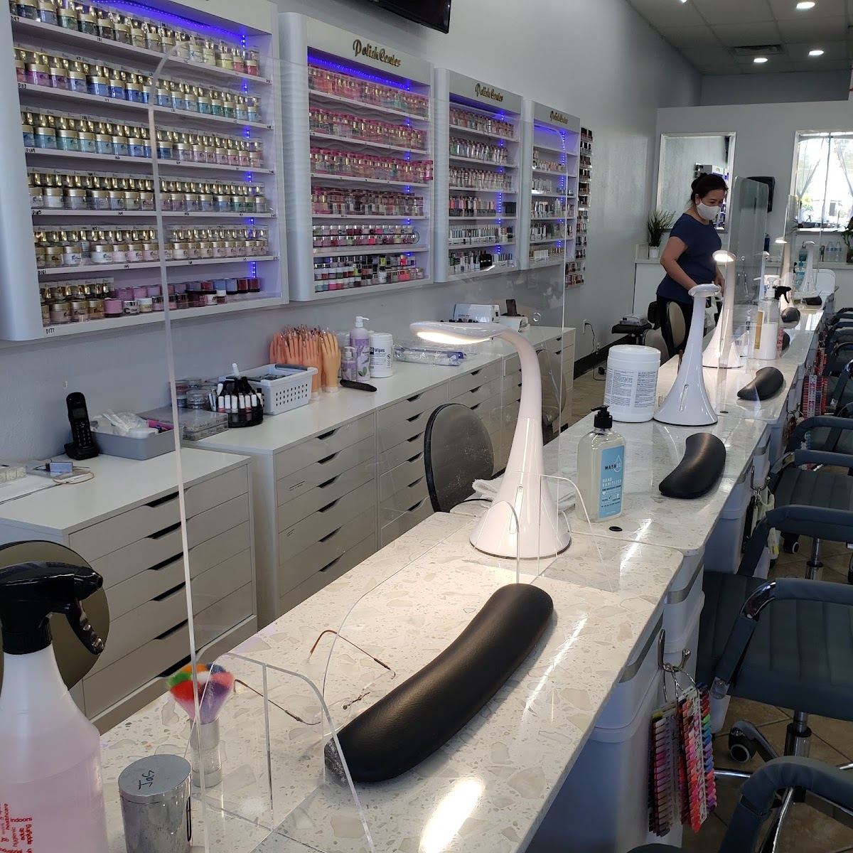 Inside Hayden Nails & Spa: white marble manicure stations in front of walls of polish