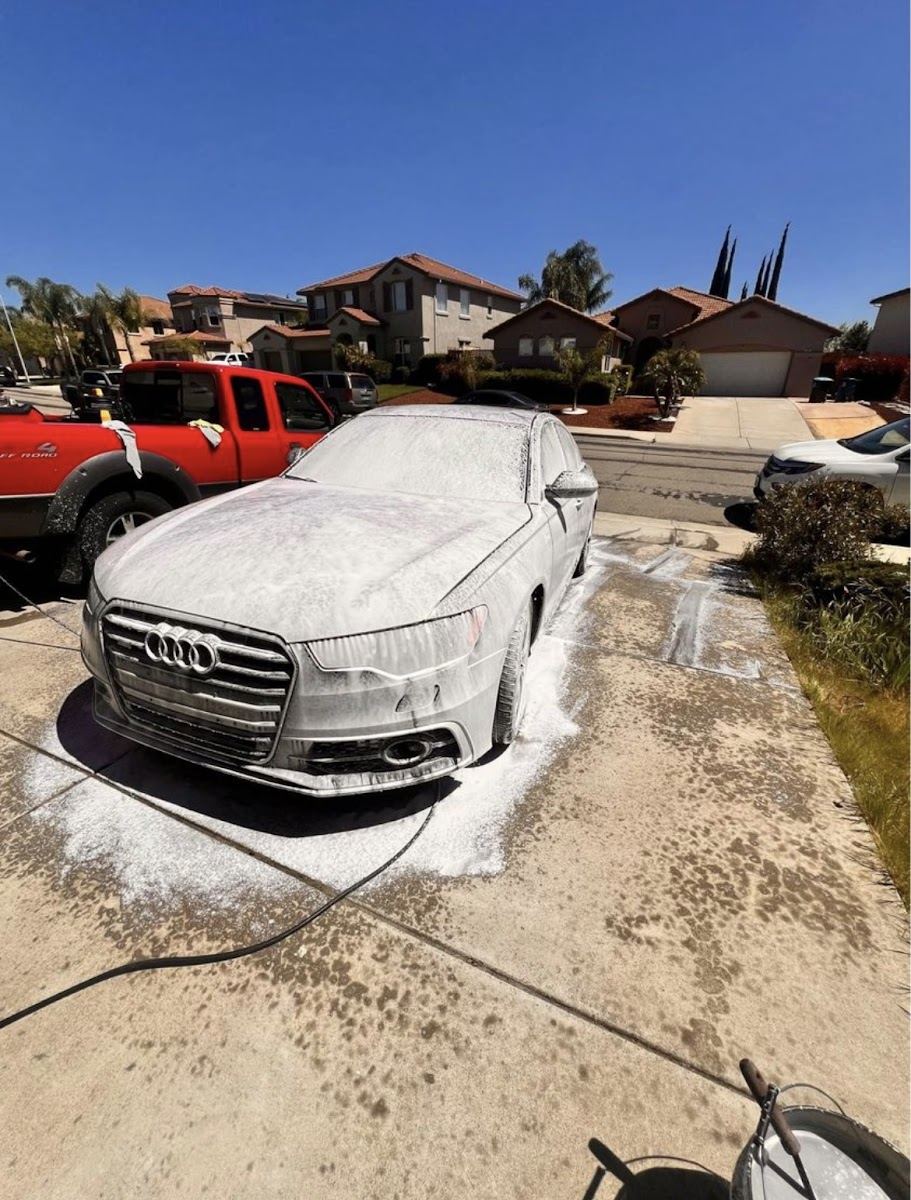 Audi sedan under a thick layer of foam in a driveway