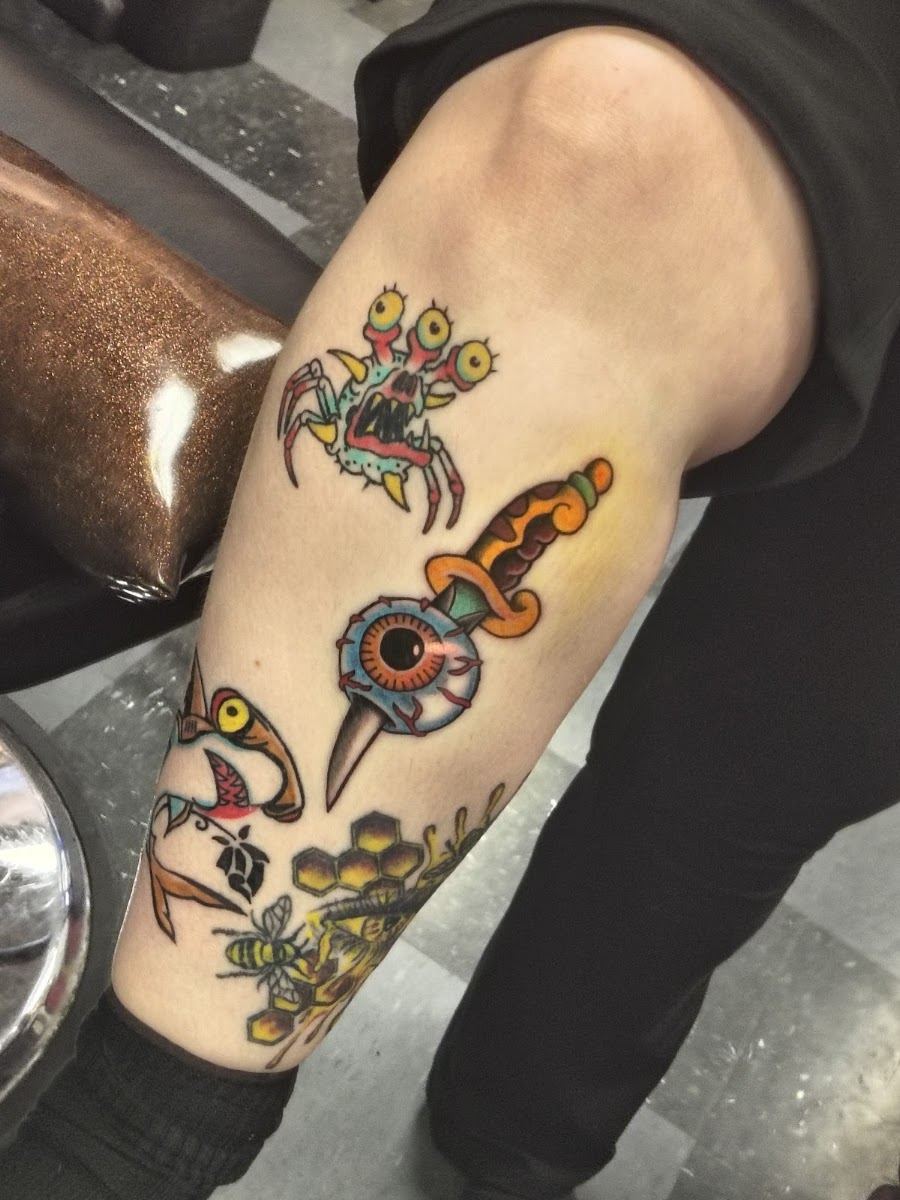 Colorful traditional flash tattoos on a lower leg: dagger, eye and spider