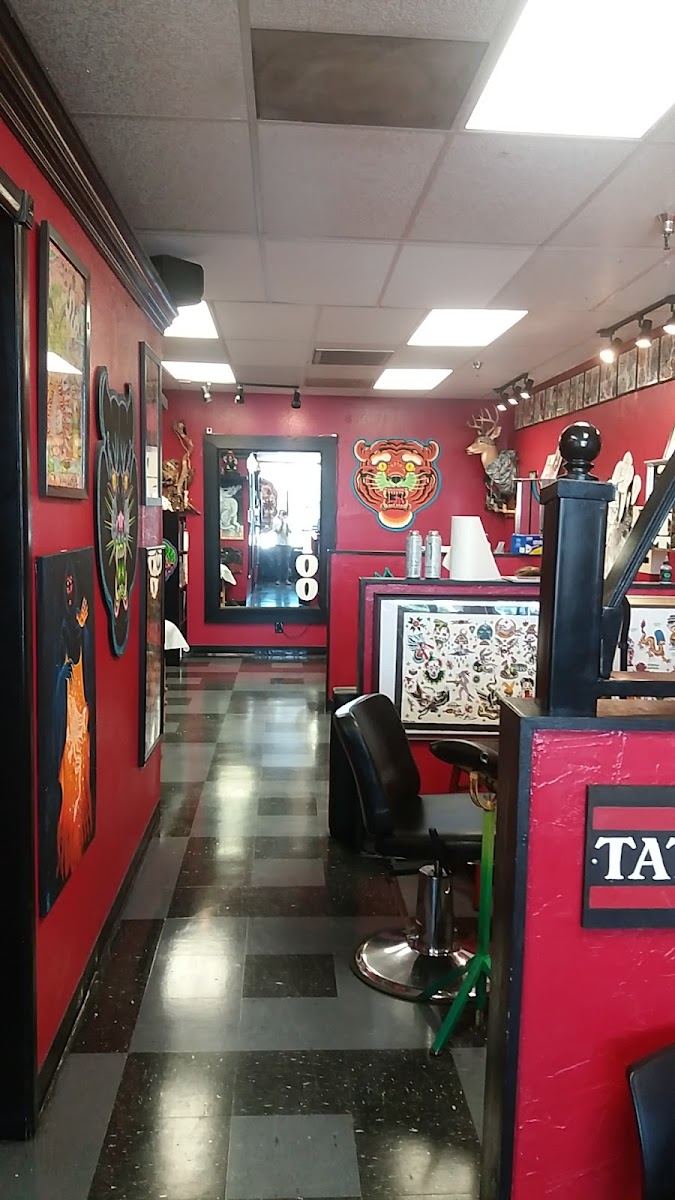 Long view of the shop floor with red walls lined with flash and tattoo stations