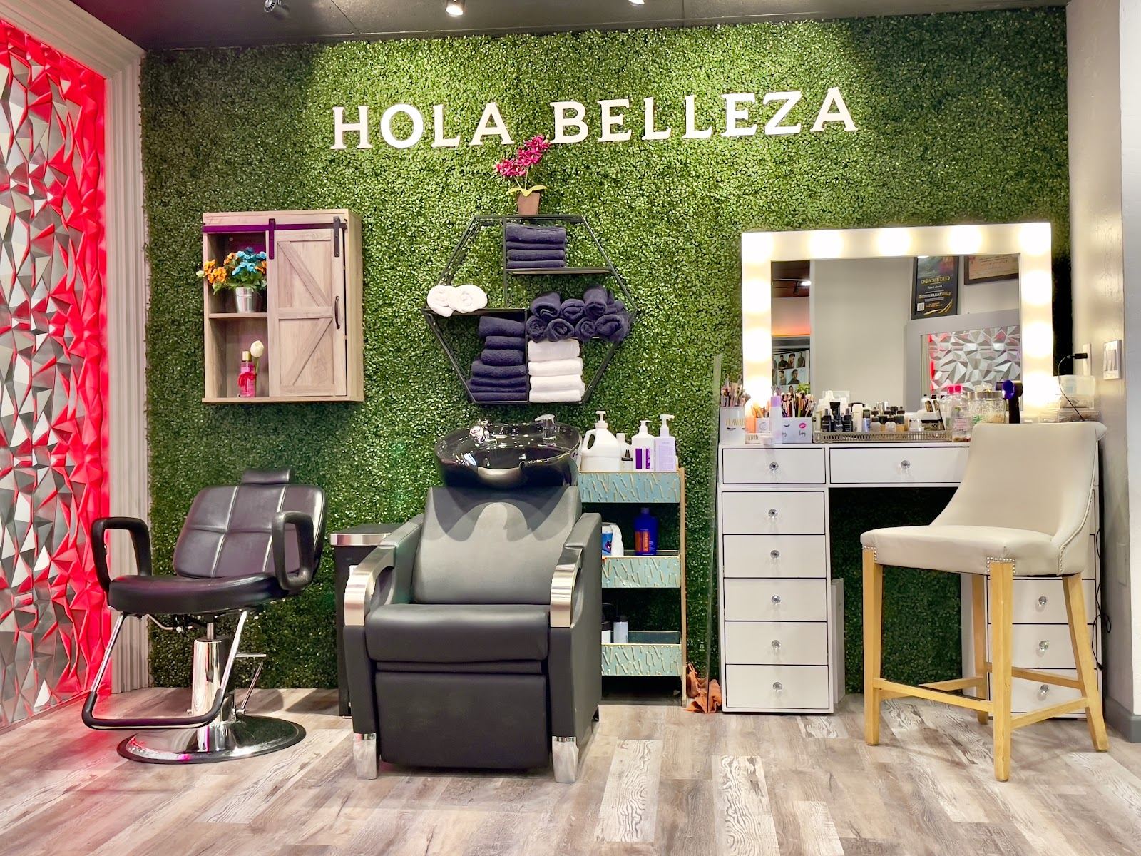 Styling station with a green leaf wall reading Hola Belleza