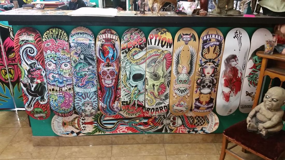 Row of hand painted skate decks with skulls and traditional art on the shop counter