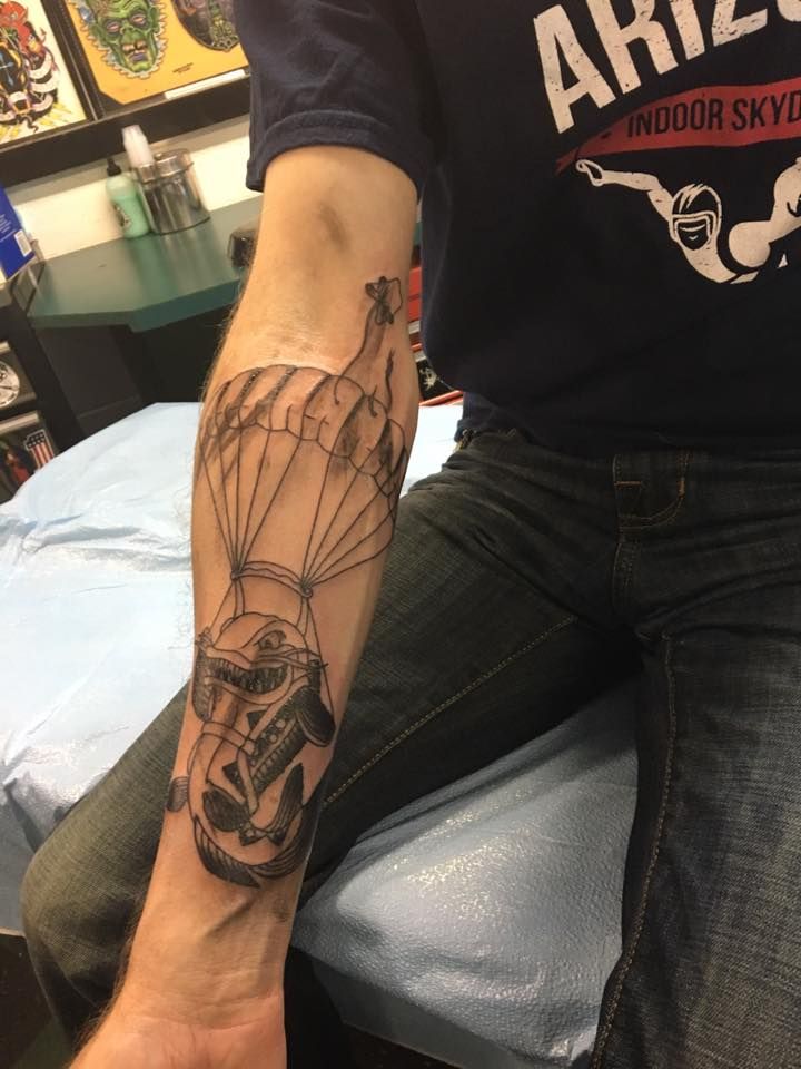 Black and grey tattoo on a forearm, client seated in the shop