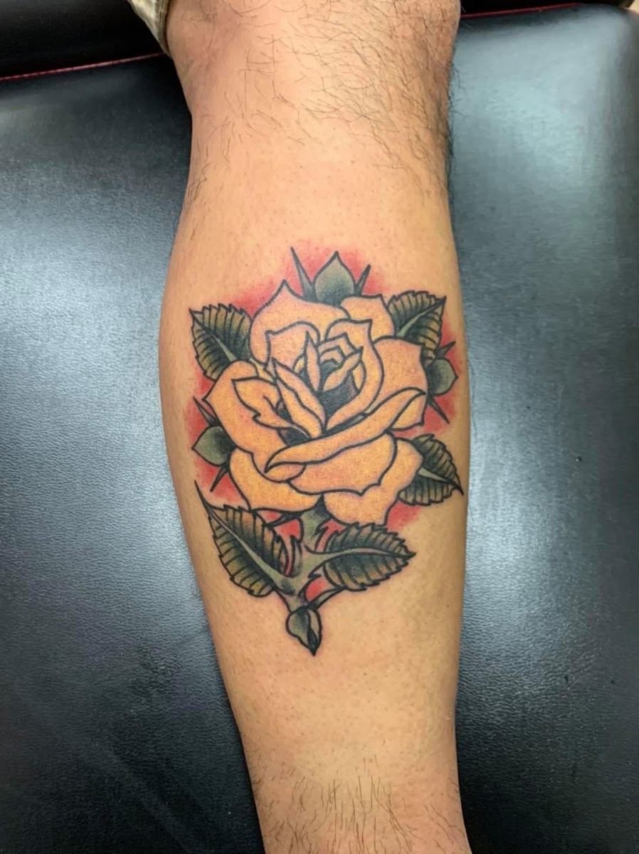 Traditional yellow rose tattoo on a forearm