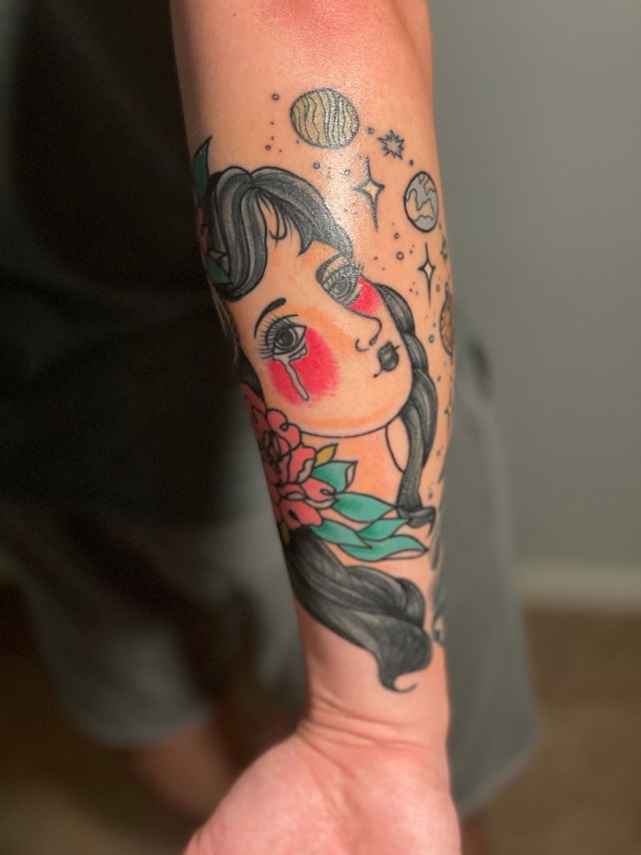 Traditional lady head tattoo with stars and planets on a forearm