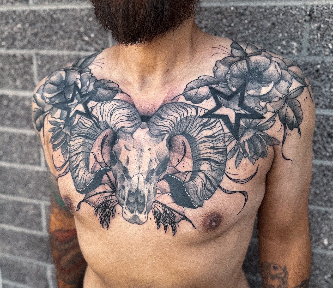 Chest piece: ram skull with curled horns, peonies and stars across the chest
