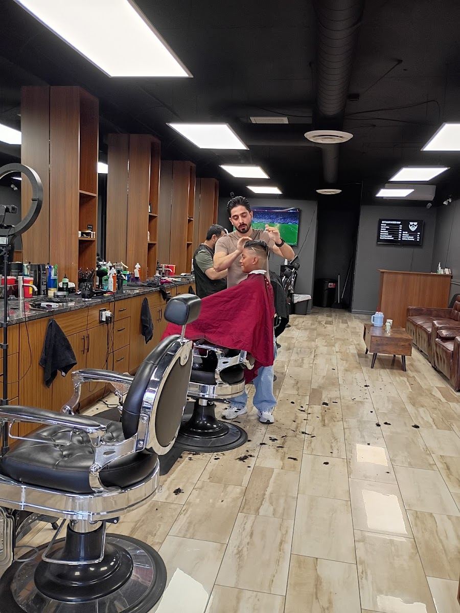Barber working on a client in a red cape inside the shop