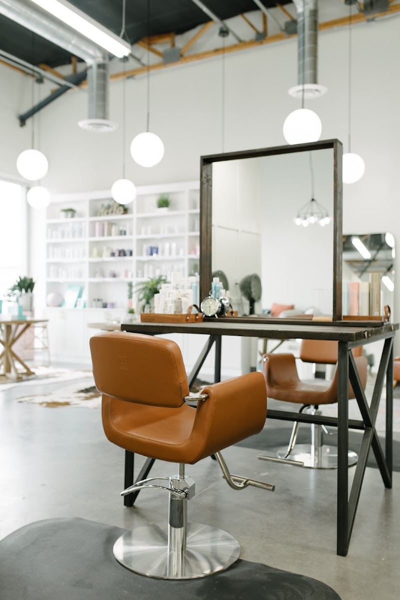 Cognac leather styling chair at a black framed mirror station