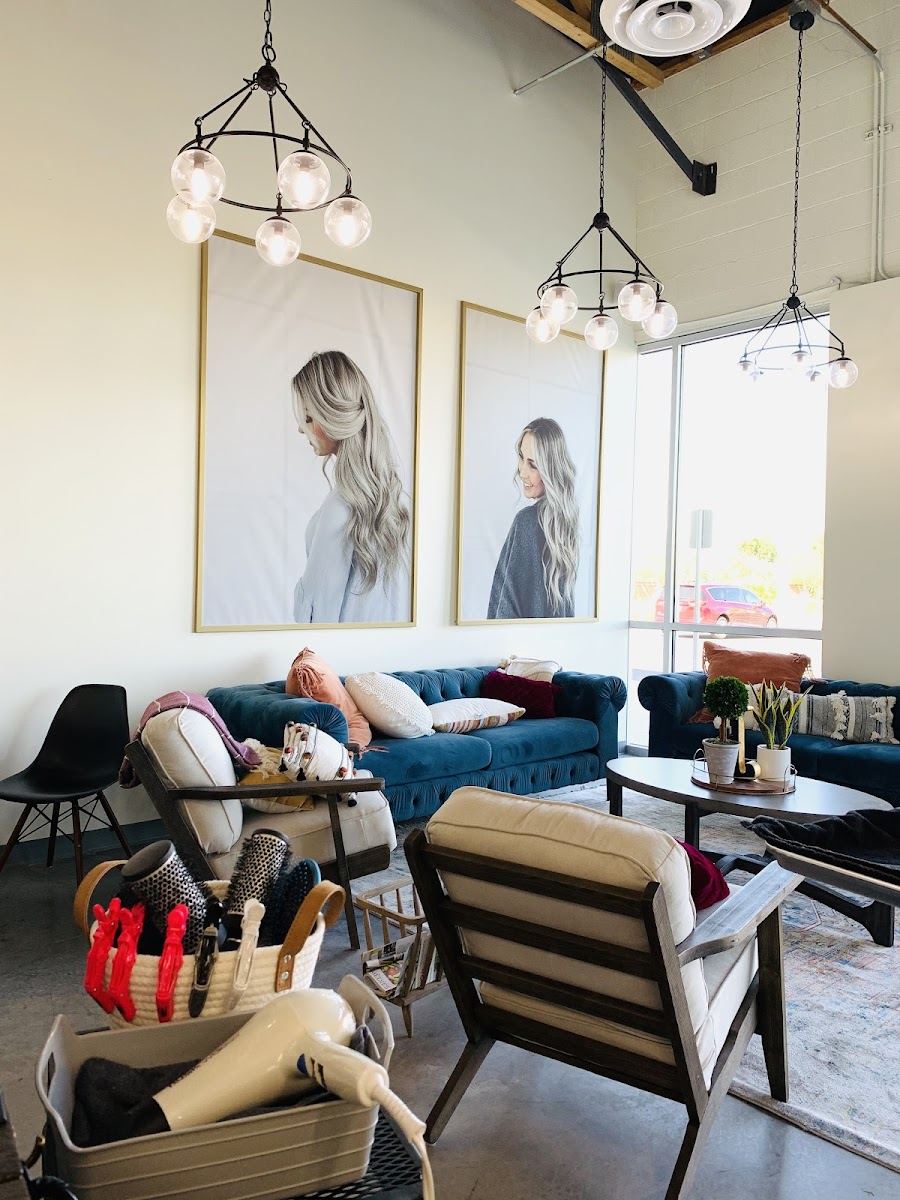 Seating area with velvet sofa, striped chairs and large portrait prints on the wall