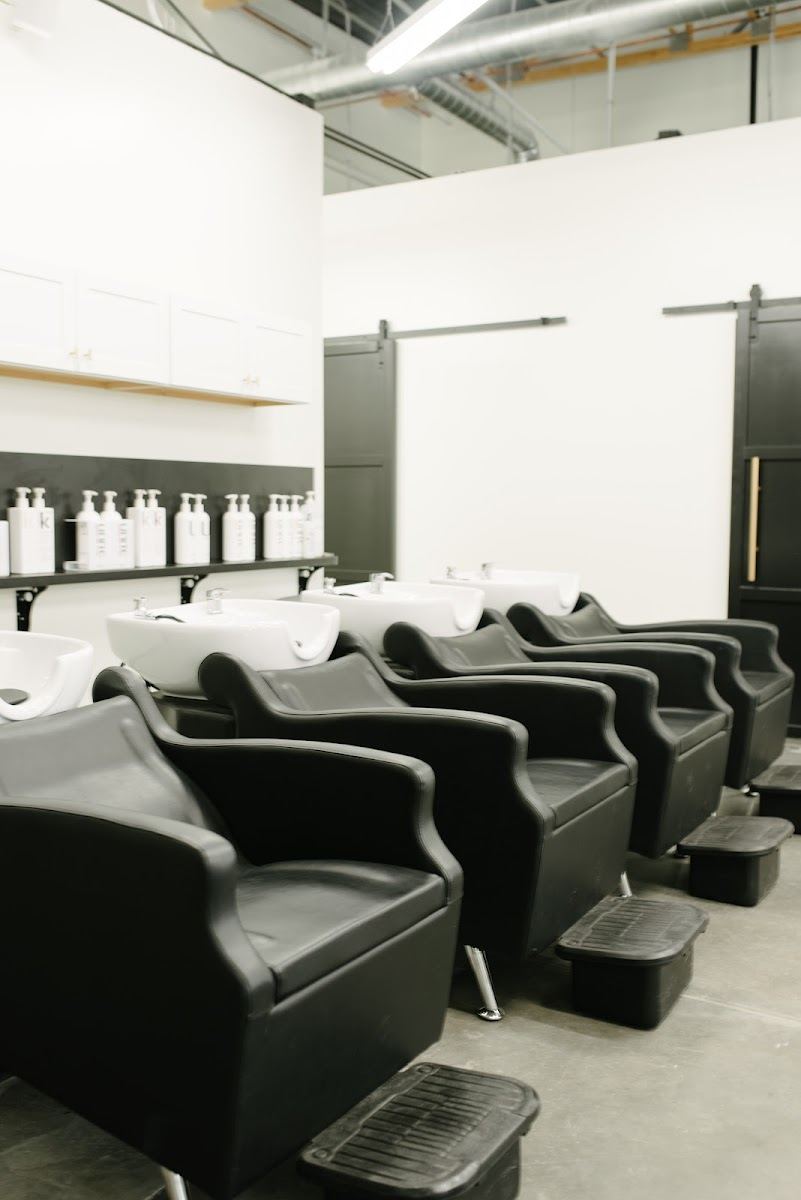 Row of black shampoo chairs at the wash bar