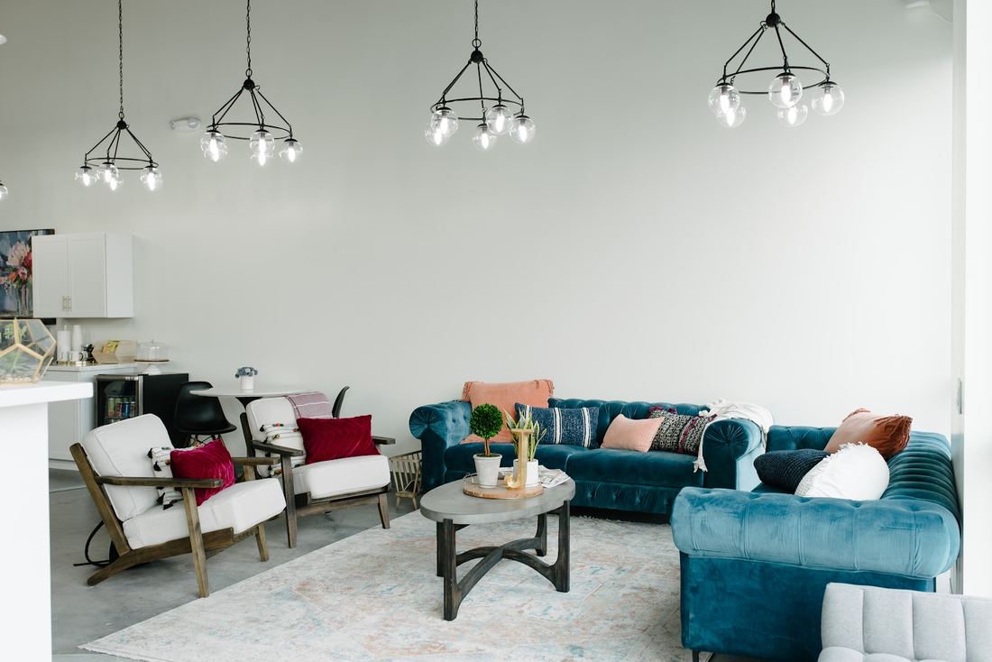 Lounge with teal velvet sofas, white armchairs and globe chandeliers