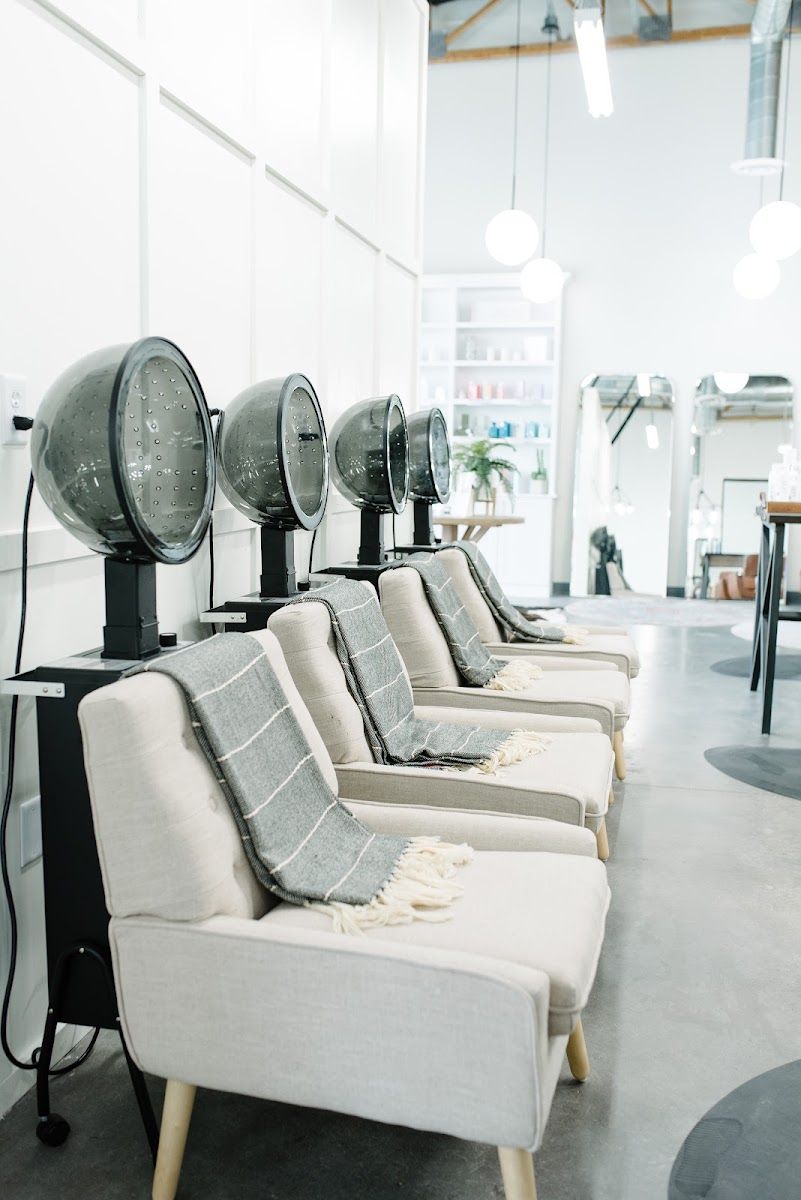 Row of cream upholstered dryer chairs with hooded dryers