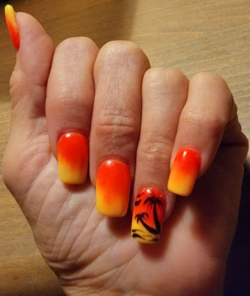Orange to yellow sunset ombre nails with a palm tree accent