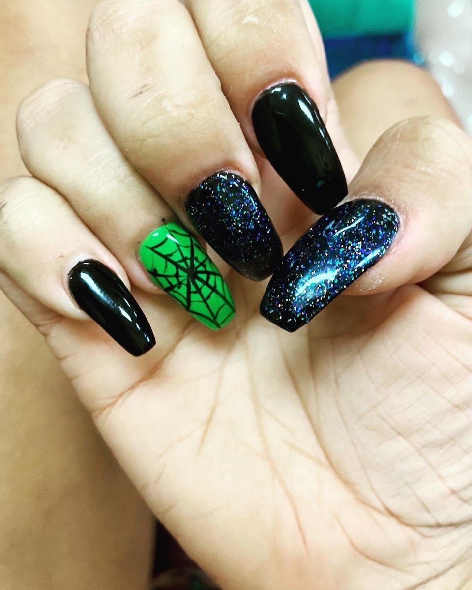 Black coffin nails with galaxy glitter and a green spiderweb accent