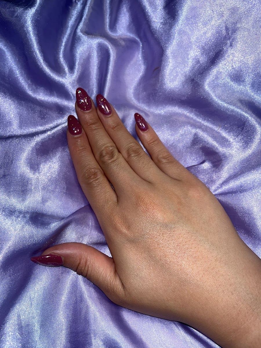 Deep burgundy almond nails resting on lavender satin