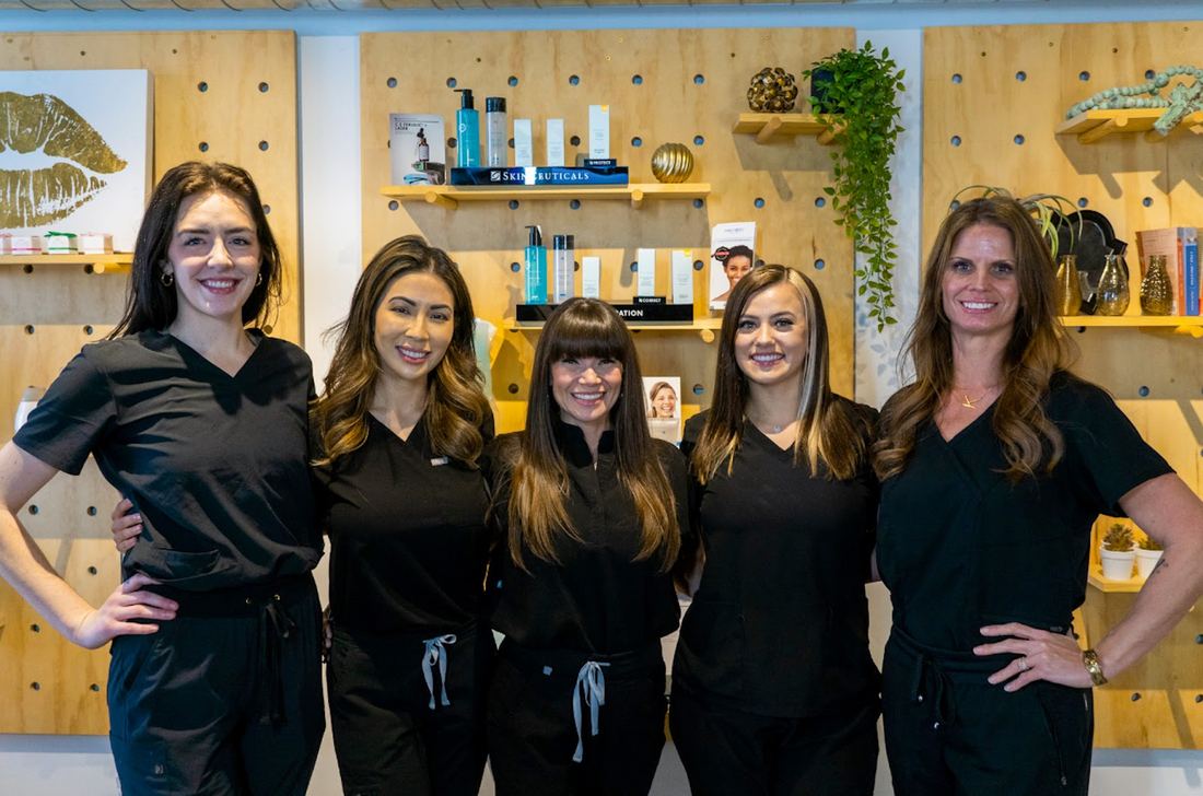 Five women in black scrubs in front of the pegboard product wall