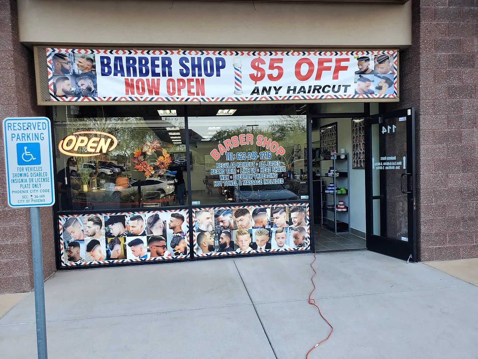 The Kingsman storefront at suite 114 with an OPEN sign and haircut posters in the windows