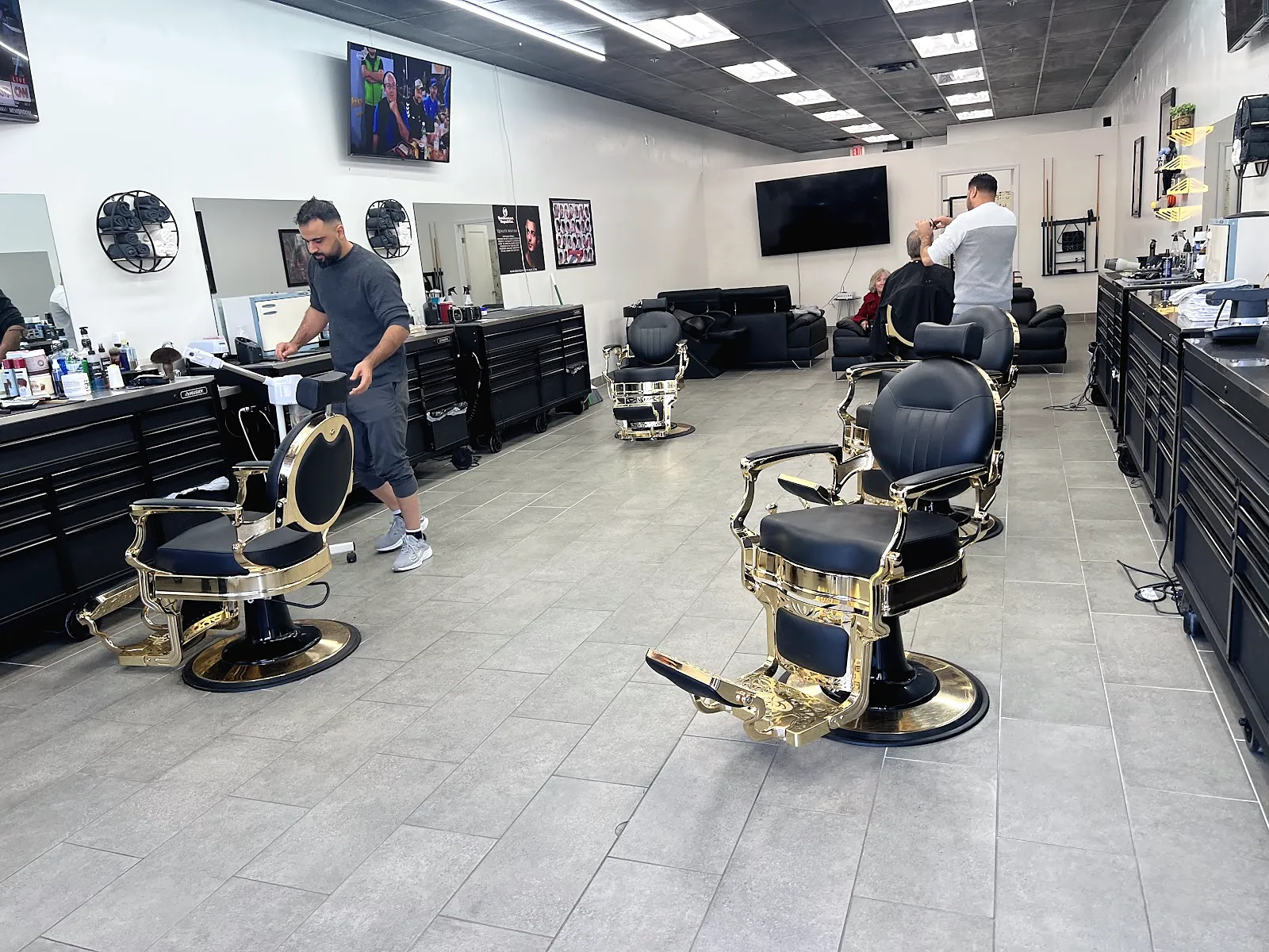 The shop floor with rows of gold and black barber chairs and black tool cabinets