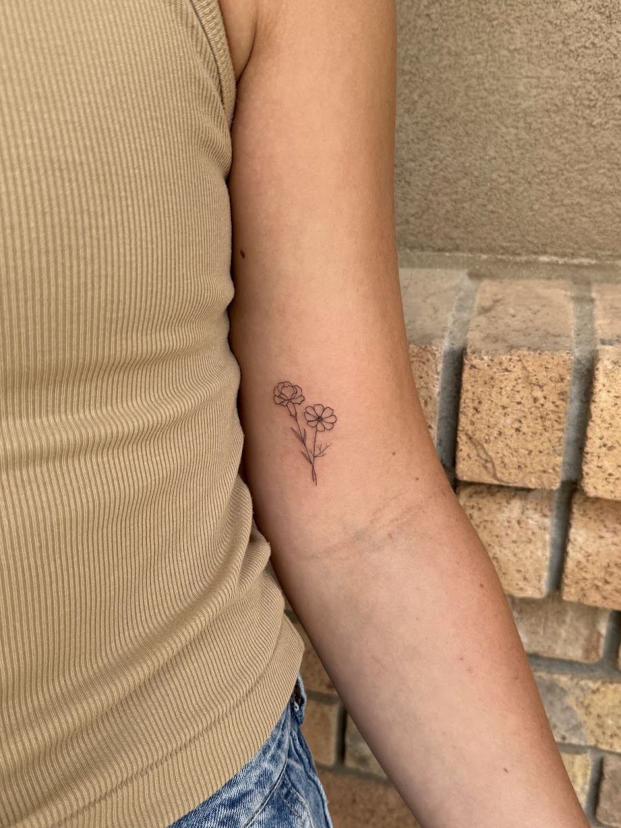 Tiny fine line flower tattoo on a forearm