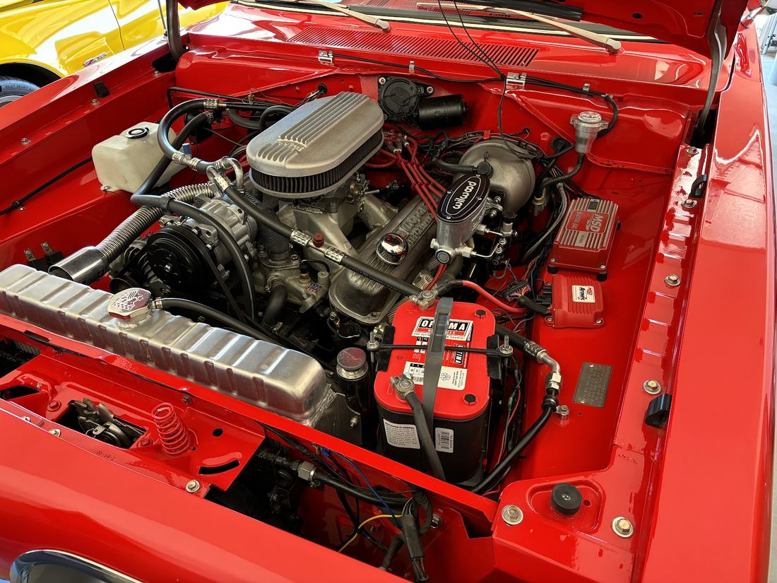 Red classic car engine bay with a V8 engine and red battery