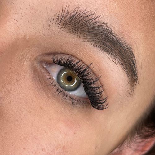 Wispy volume lash extensions on a green eye