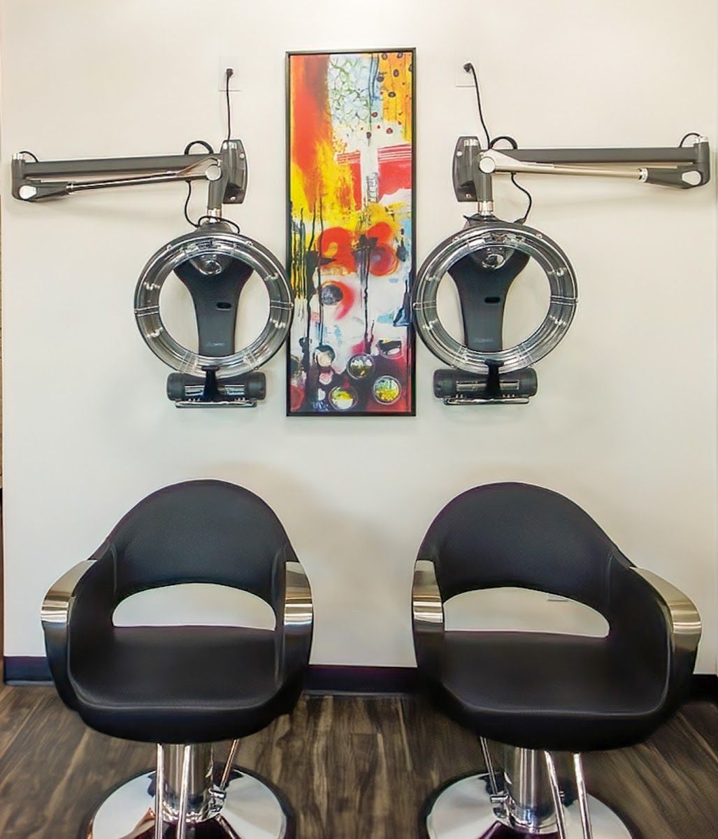 Two hooded dryer chairs beside a colorful painting