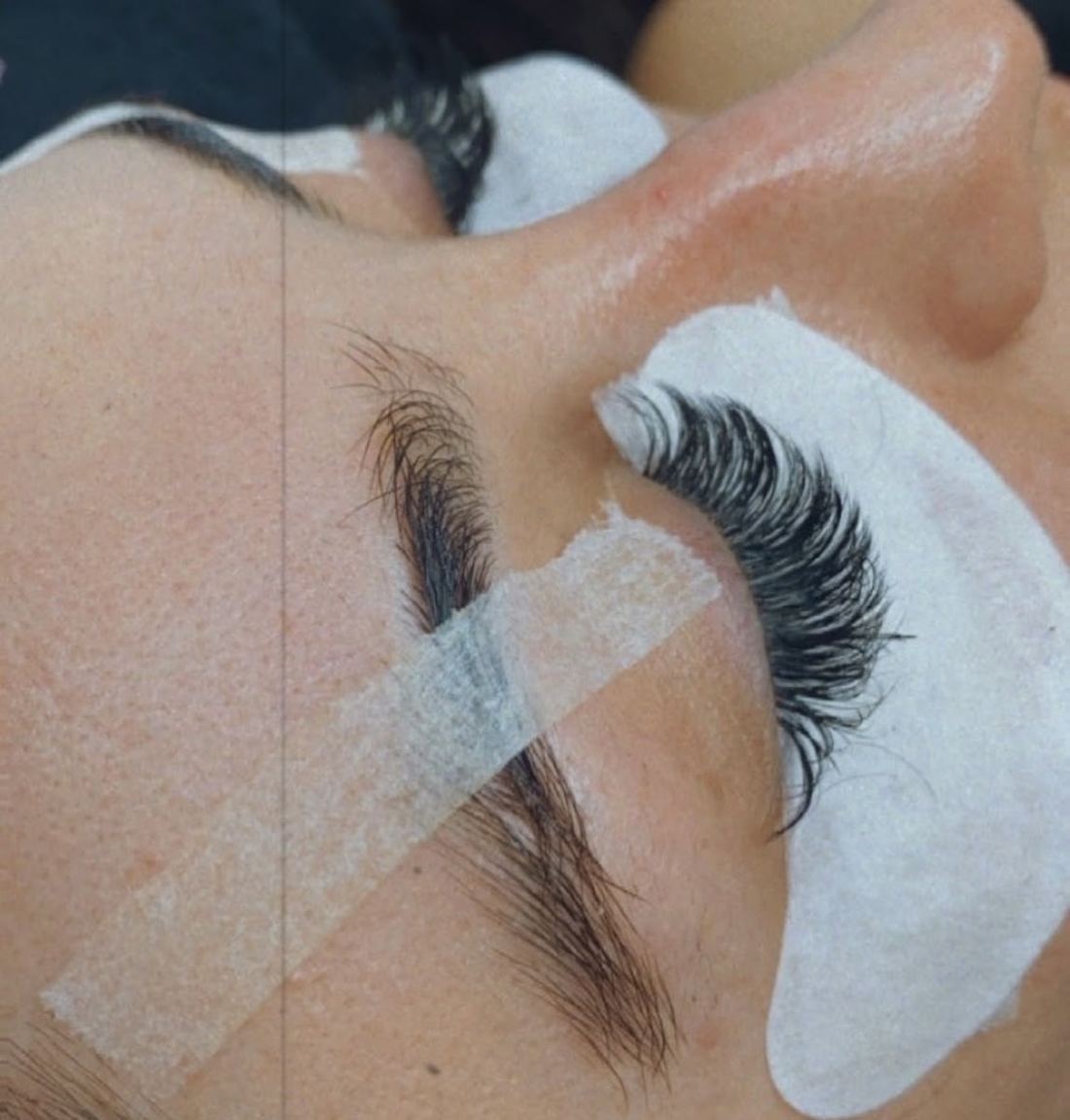 Lashes taped and isolated under a gel pad during an appointment