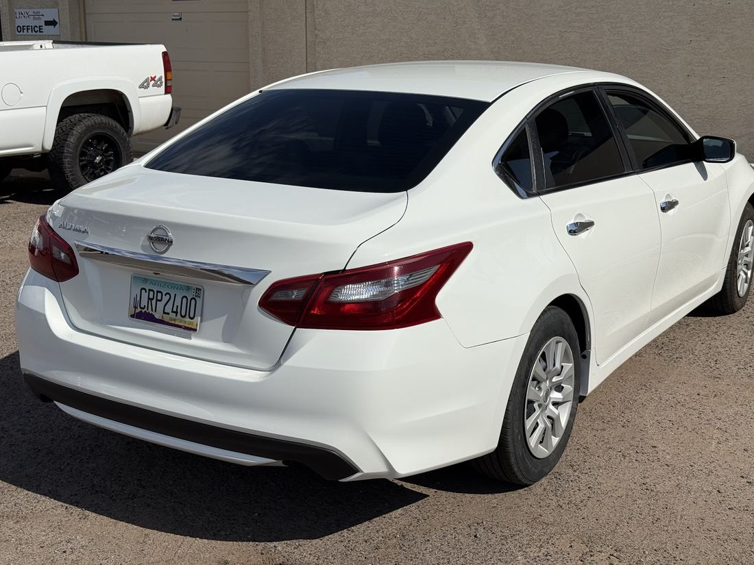 The same white sedan with a straight rear bumper and intact tail lights