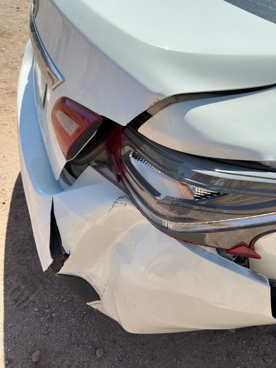 White sedan with a crushed rear bumper and broken tail light