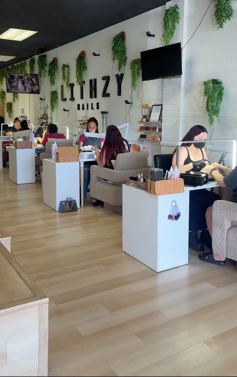 Inside LITHZY NAILS: white nail stations, hanging greenery and the LITHZY NAILS wall sign