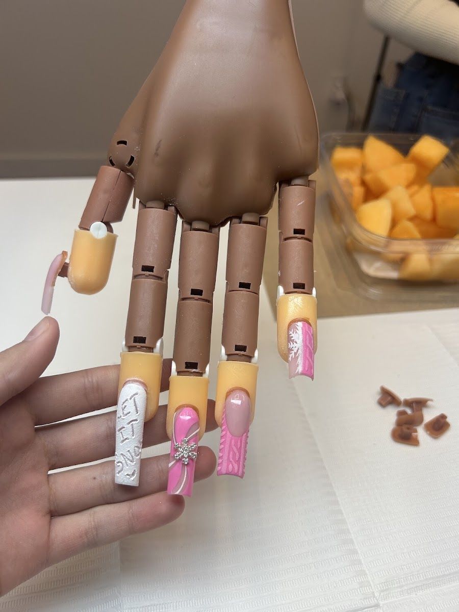 Practice hand with sculpted pink and white nail sets from a nail class