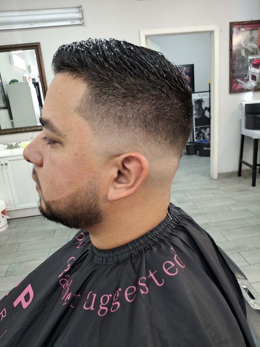 Side profile of a client with a clean low fade blended into a slicked top and a trimmed beard