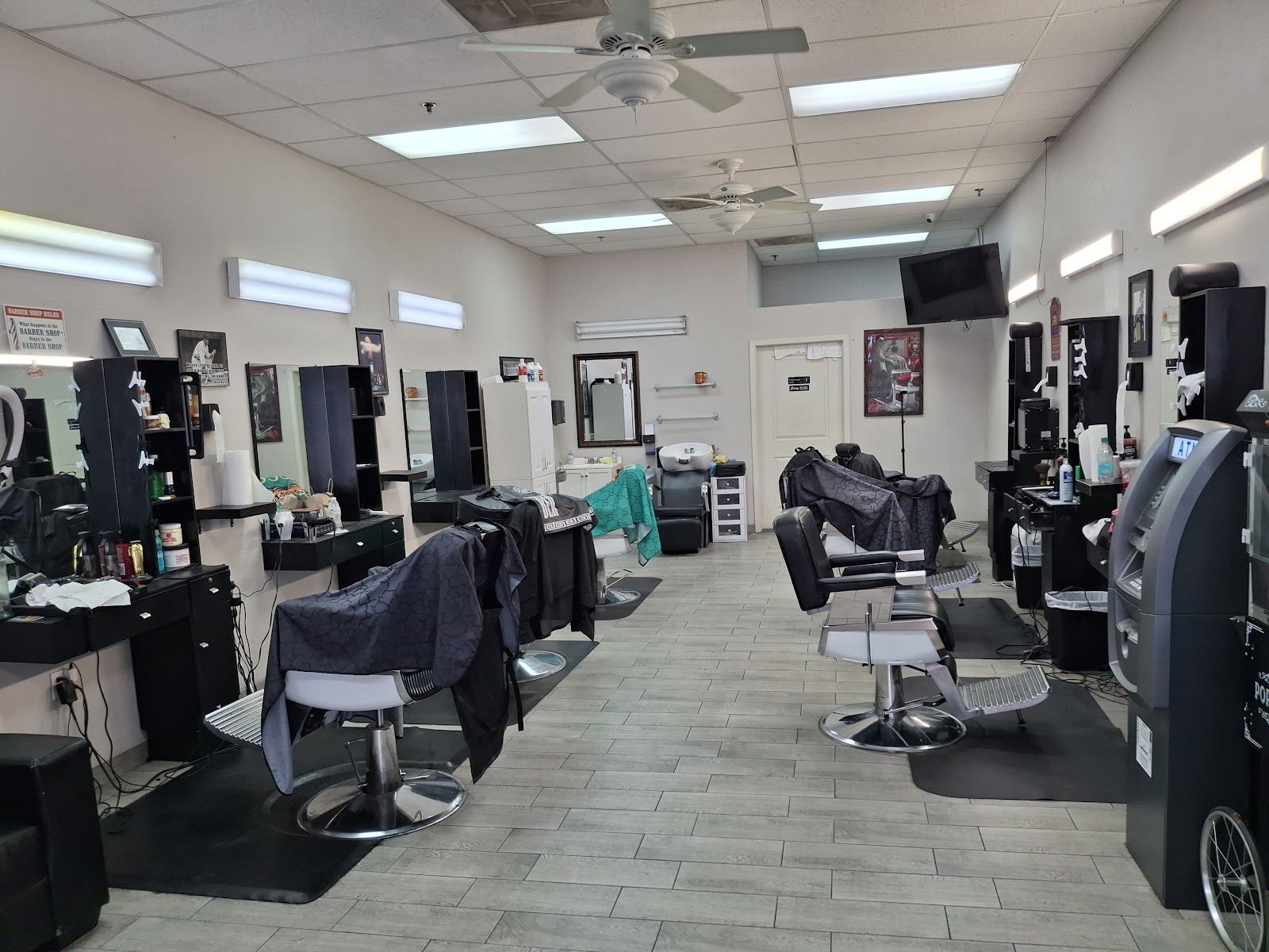 Inside Master Cut Barber: a long bright room lined with black barber chairs and mirrored stations