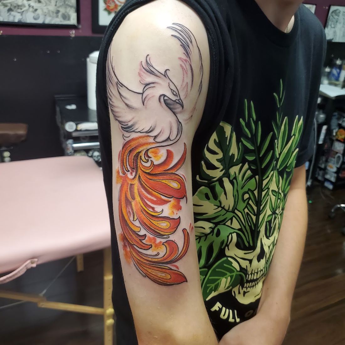 Phoenix tattoo in orange and red flames on an upper arm