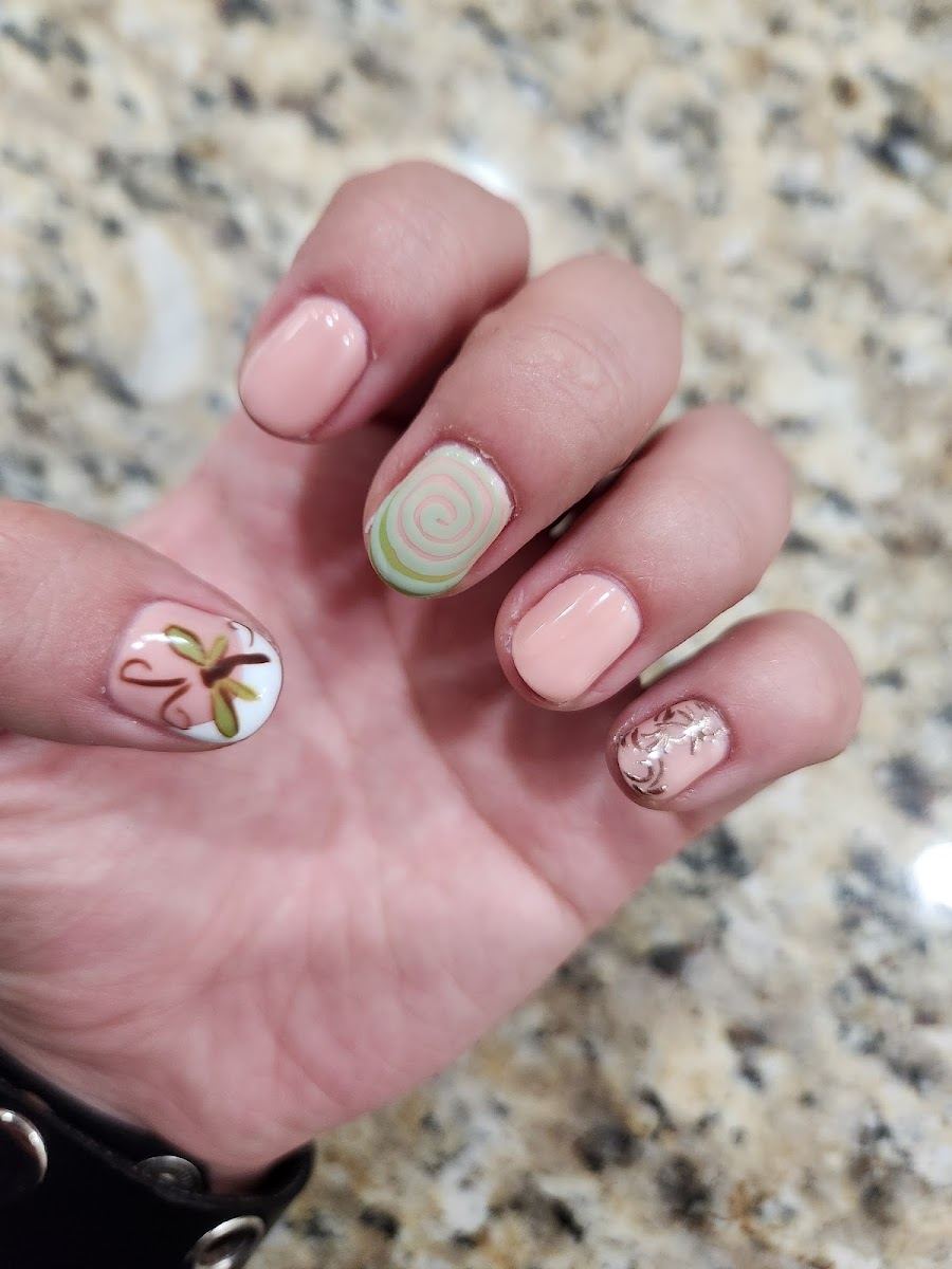 Short peach nails with a hand-painted palm and swirl accents