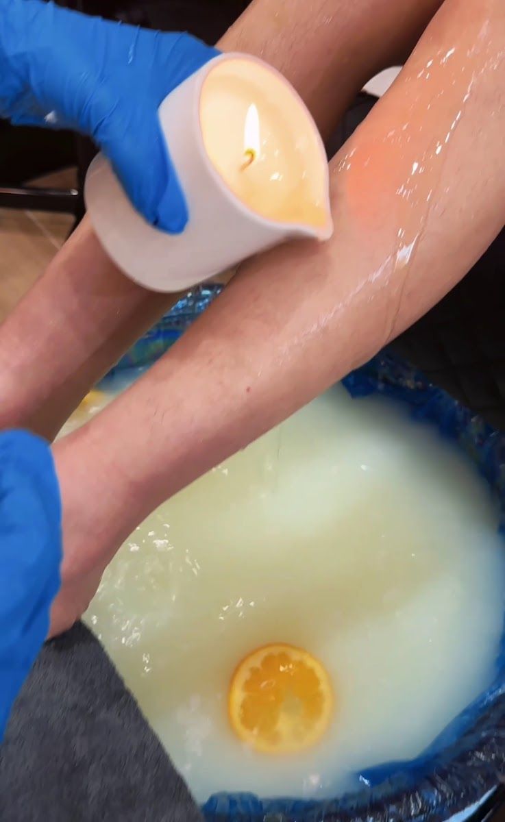 A pedicure soak with an orange slice and a warm candle being poured