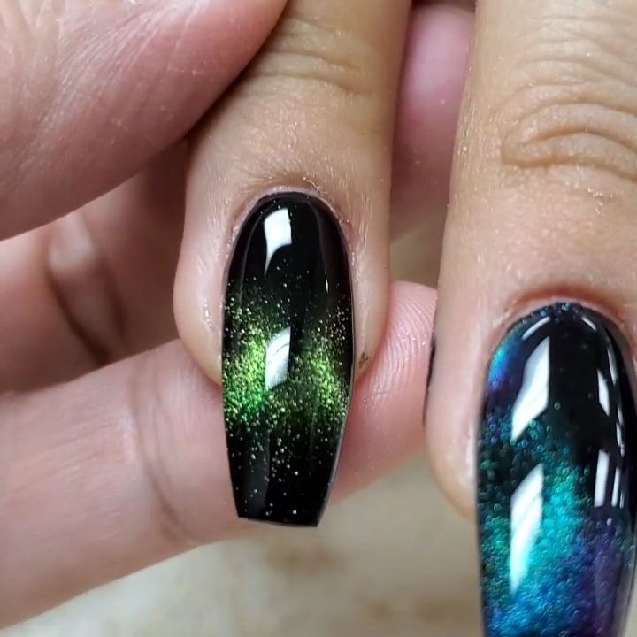 Close-up of glossy black coffin nails with a green and blue galaxy shimmer