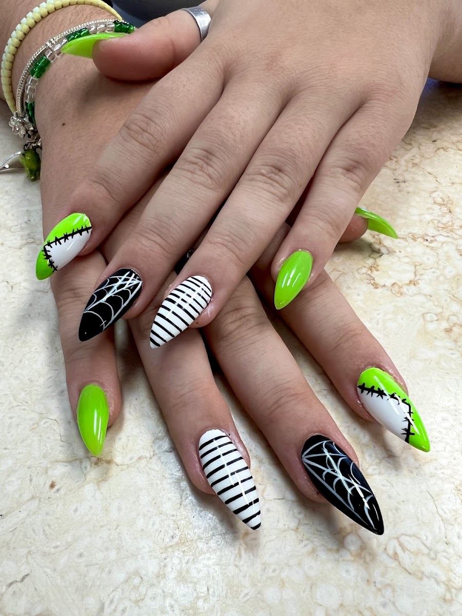 Stiletto nails in lime green, black and white stripes and spiderweb art