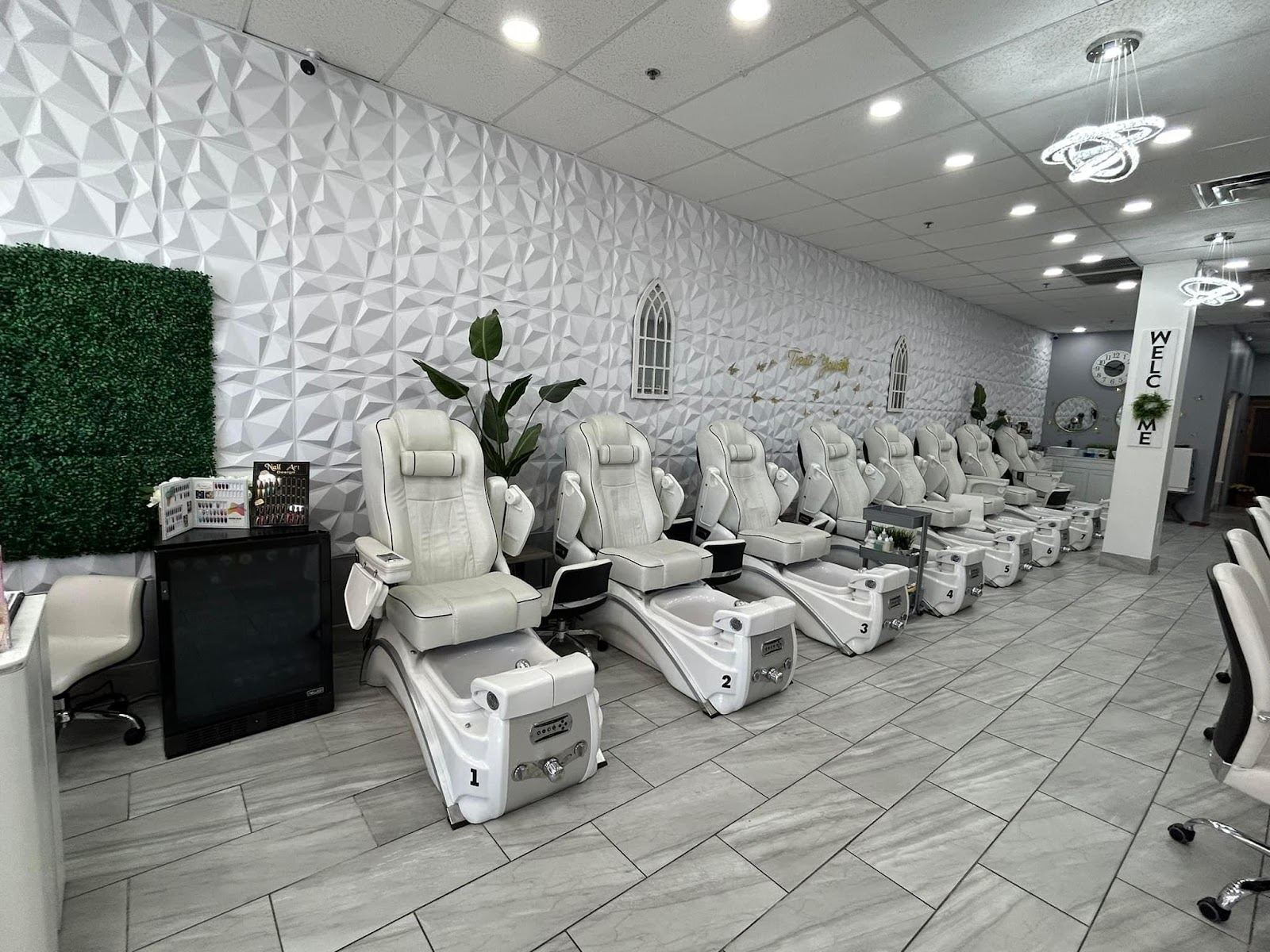 Inside Nails Creation: a row of white pedicure chairs against a white 3D tile wall