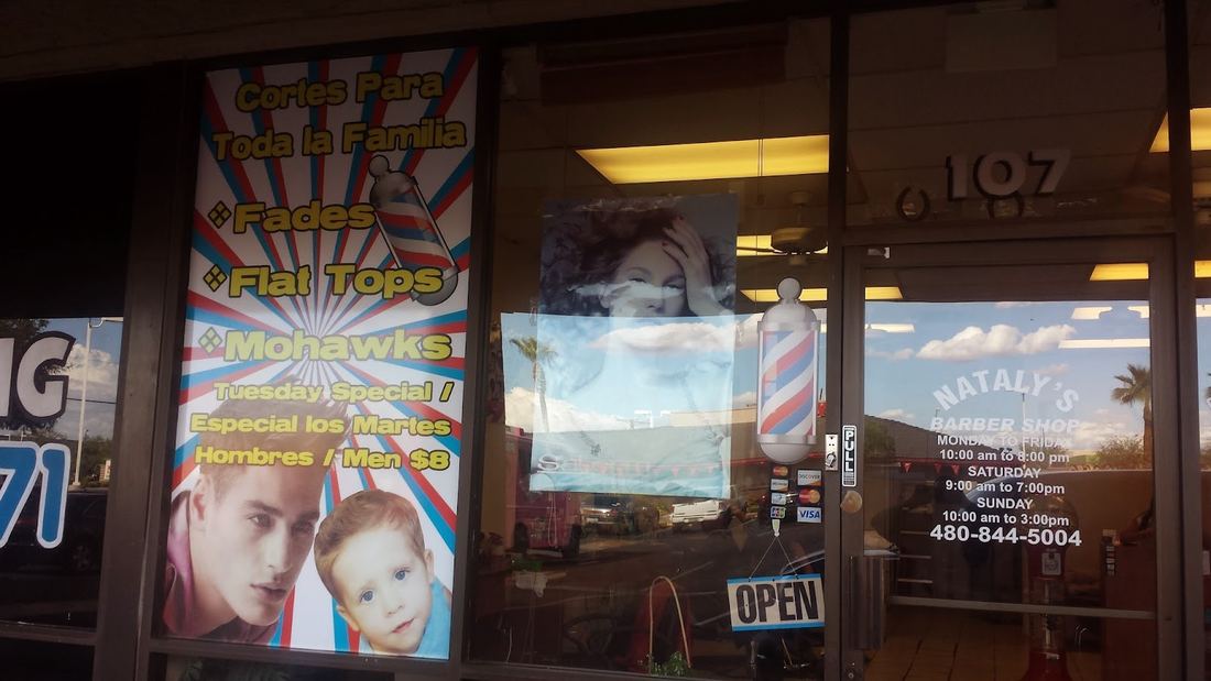 The shop window listing fades, flat tops and mohawks with a barber pole beside the door