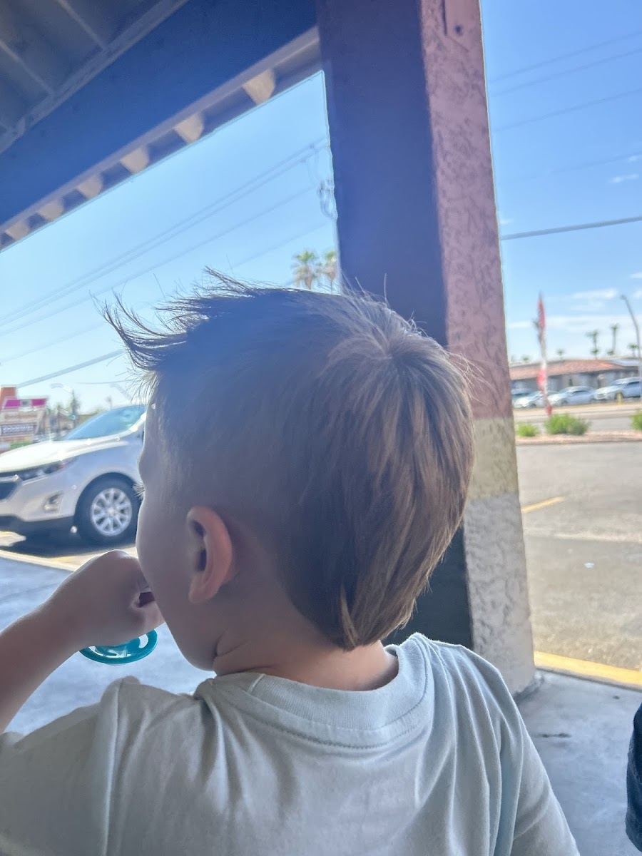 A young client showing off a fresh haircut outside the shop